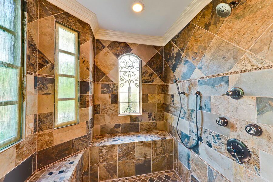built-in shower seats and decorative privacy windows in a large walk-in shower with bold tiling in Charlotte, NC