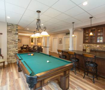 Remodeled basement with wood flooring, pool table, and bar area.