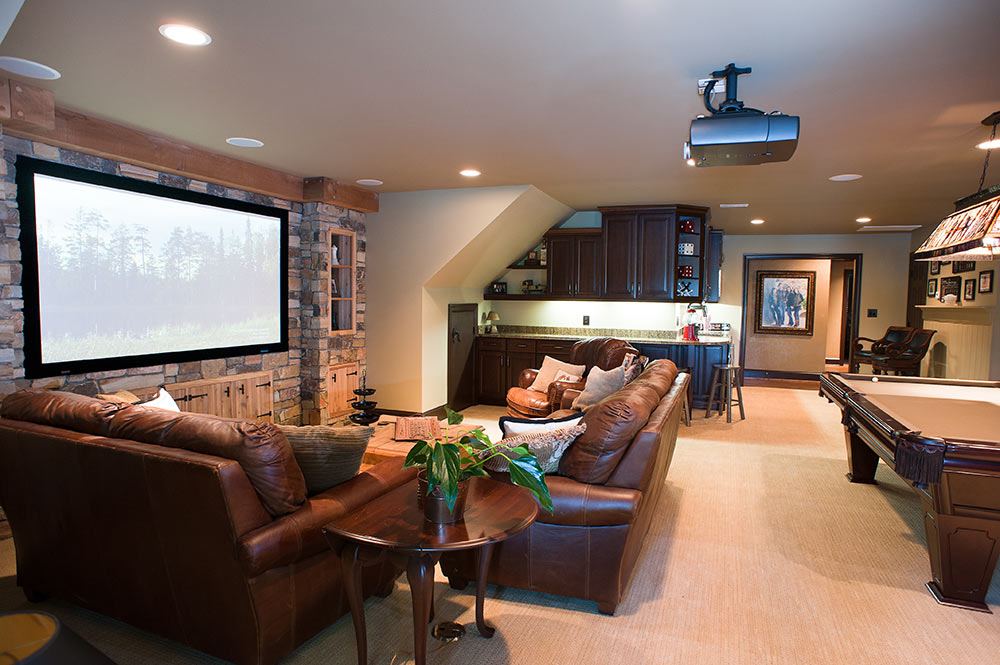 Remodeled basement with stone feature wall, brown leather couches, bar area, and pool table.