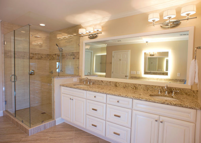 Remodeled bathroom with dual vanity, glass-enclosed shower, and large mirror.