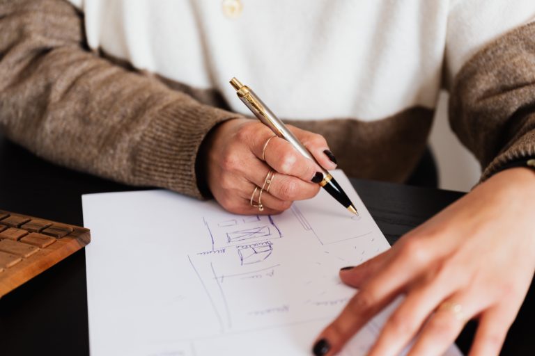 Upclose of a homeowner's hands drawing a floor plan for their upcoming remodel.