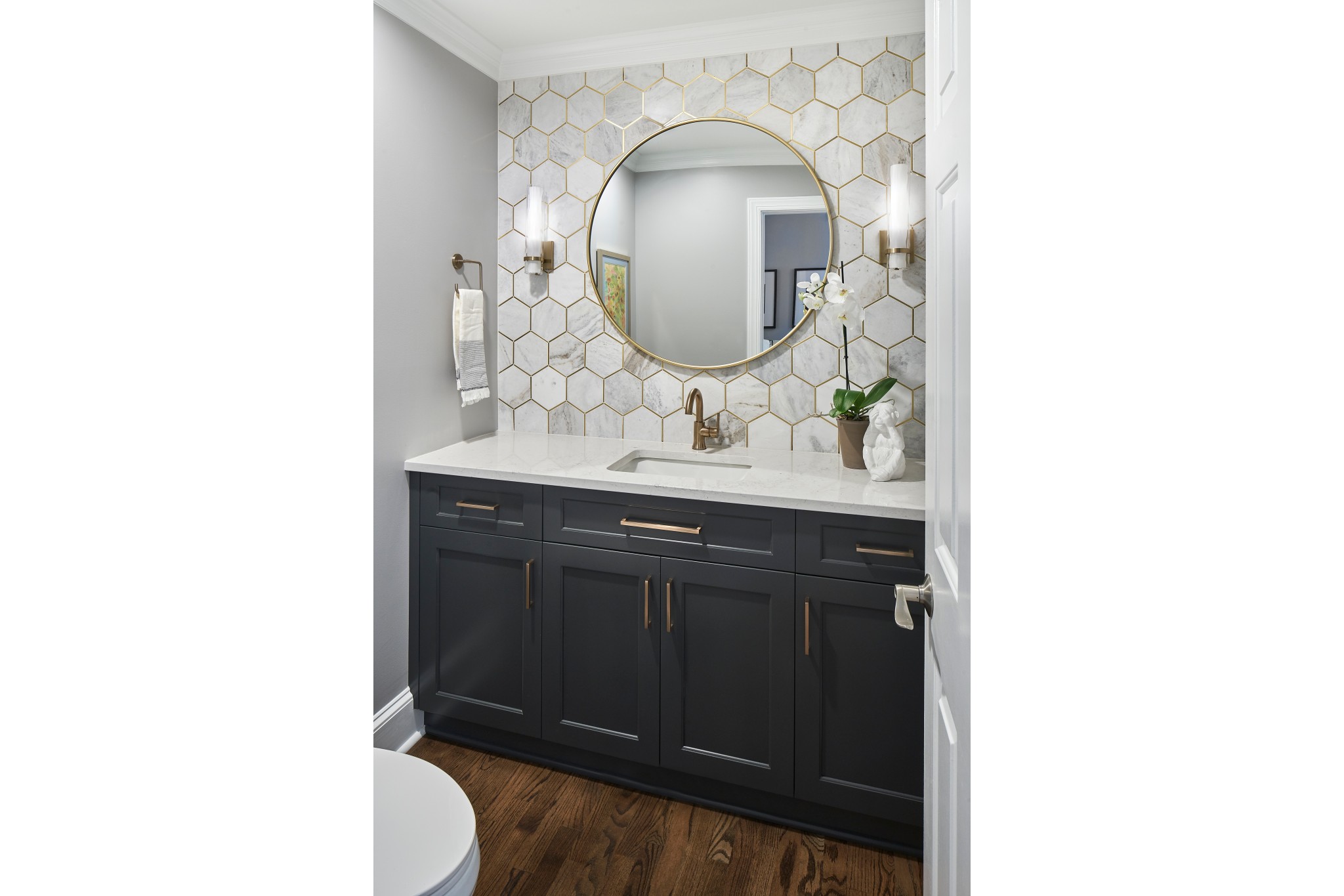 Updated bathroom with navy vanity and gold-accented mirror and backsplash