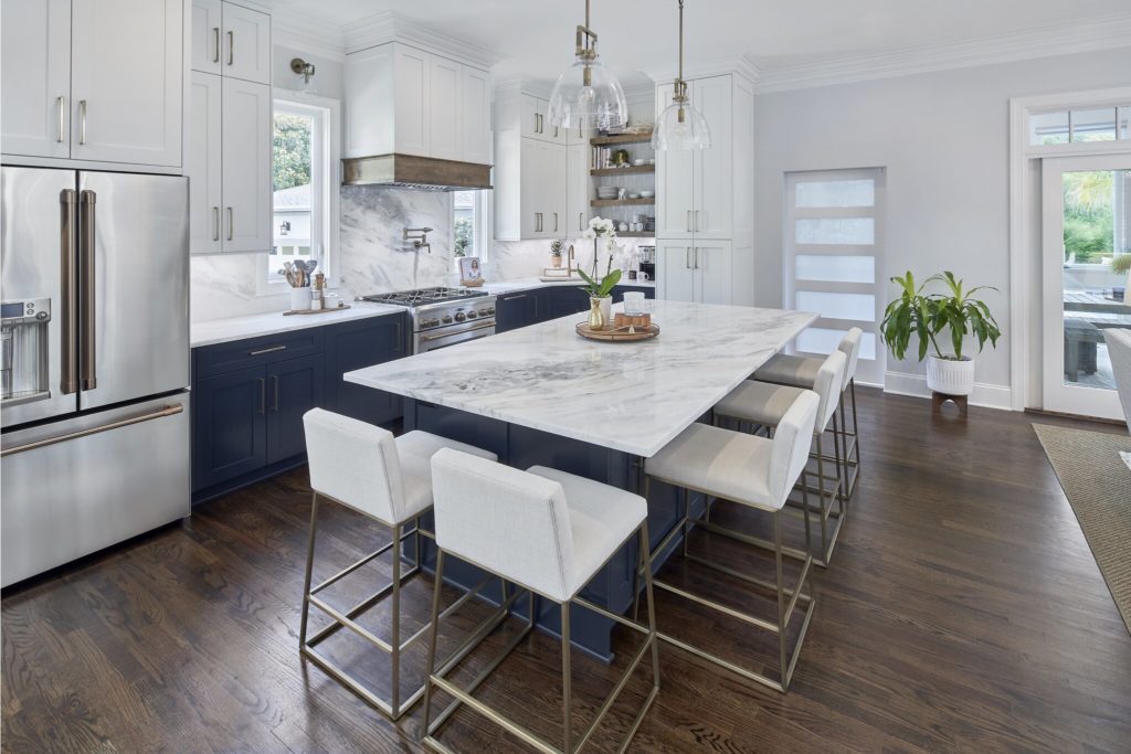 Remodeled kitchen with white countertops and blue cabinetry and dark wood floors.