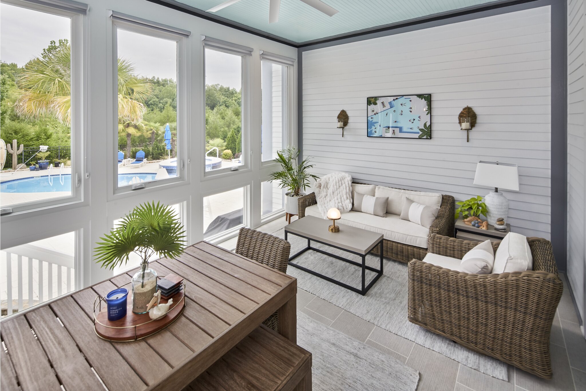 Bright updated sunroom with floor-to-ceiling windows overlooking outdoor pool