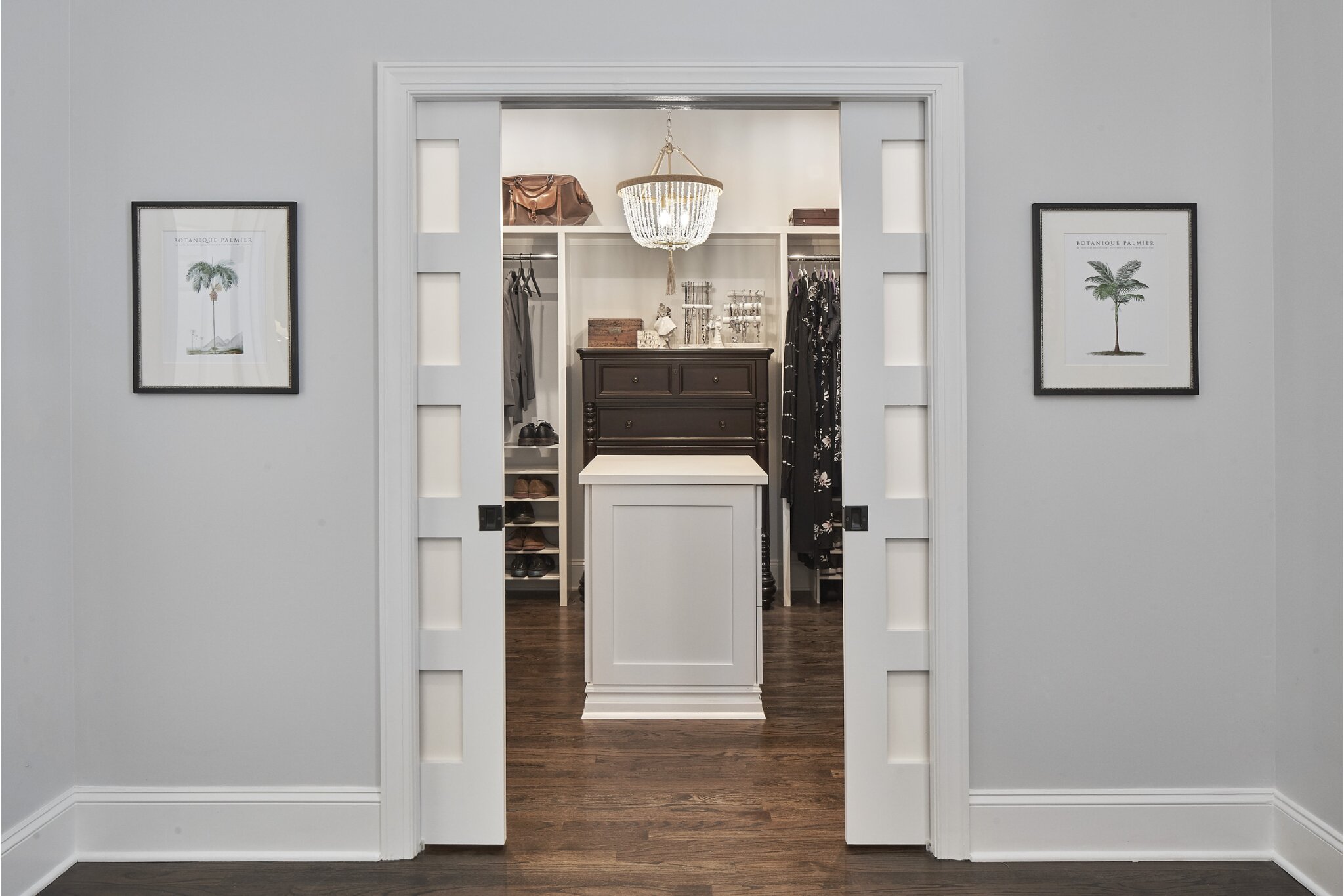 Craftsman closet upgrade with double five-panel pocket doors, custom built-ins, center island, and statement chandelier