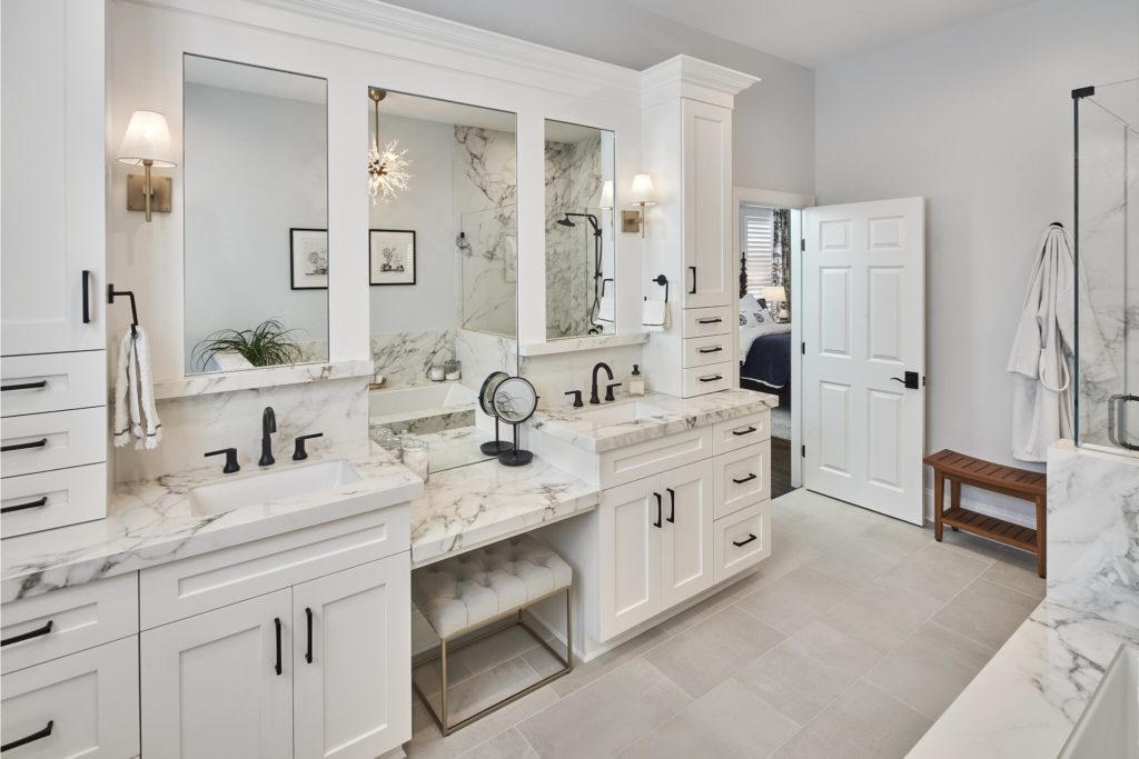 Large bathroom remodel with a white double vanity, white tile floor, and black faucets.