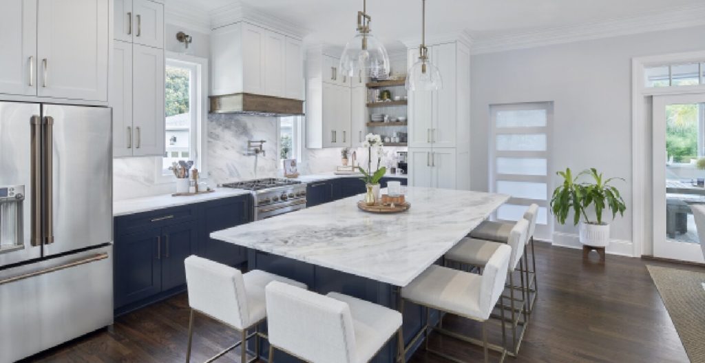 Renovated kitchen with island, blue and white cabinets, and white marble counter tops.