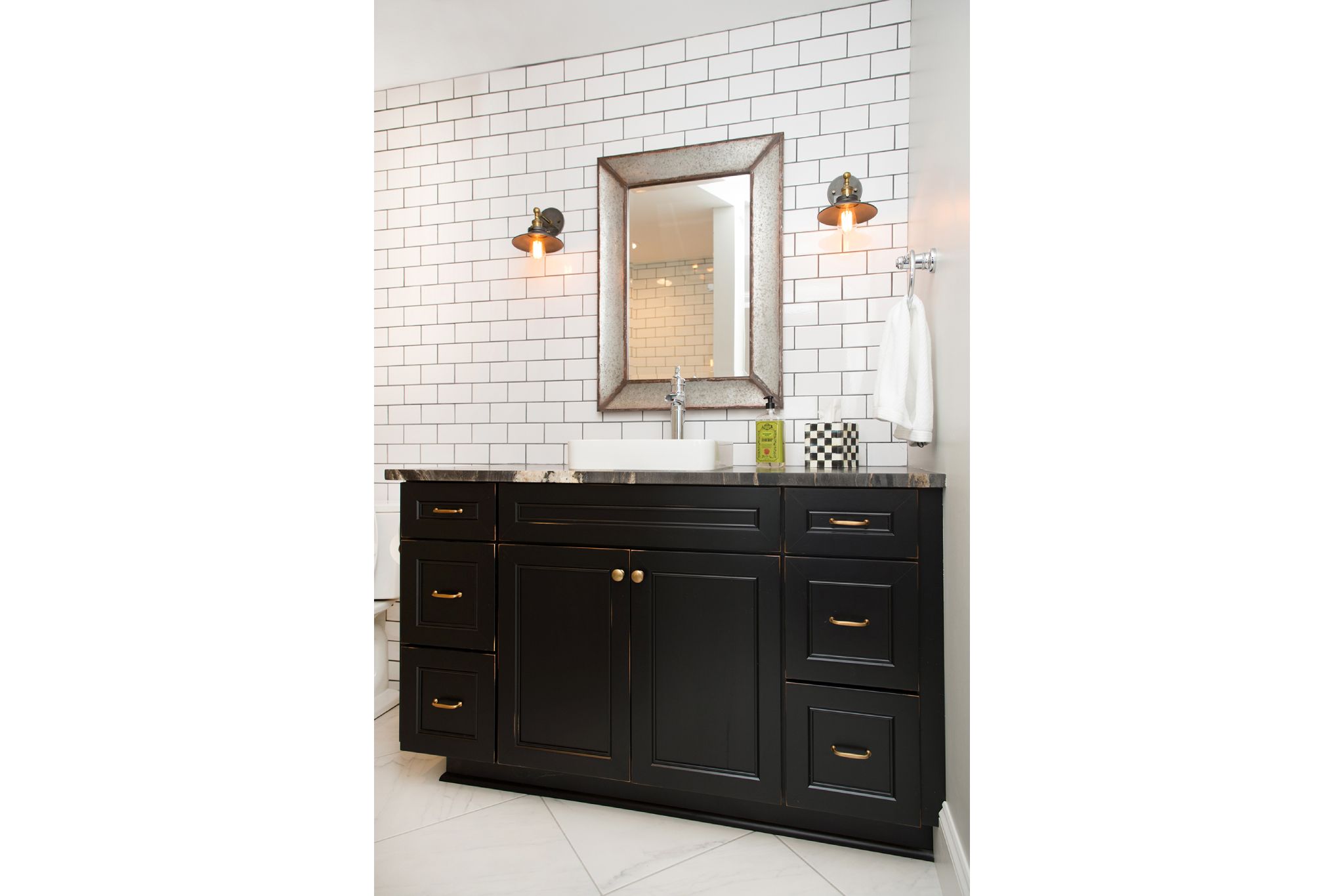 Bathroom with white subway-tiled walls and black grout, with a black and gold-accented statement vanity