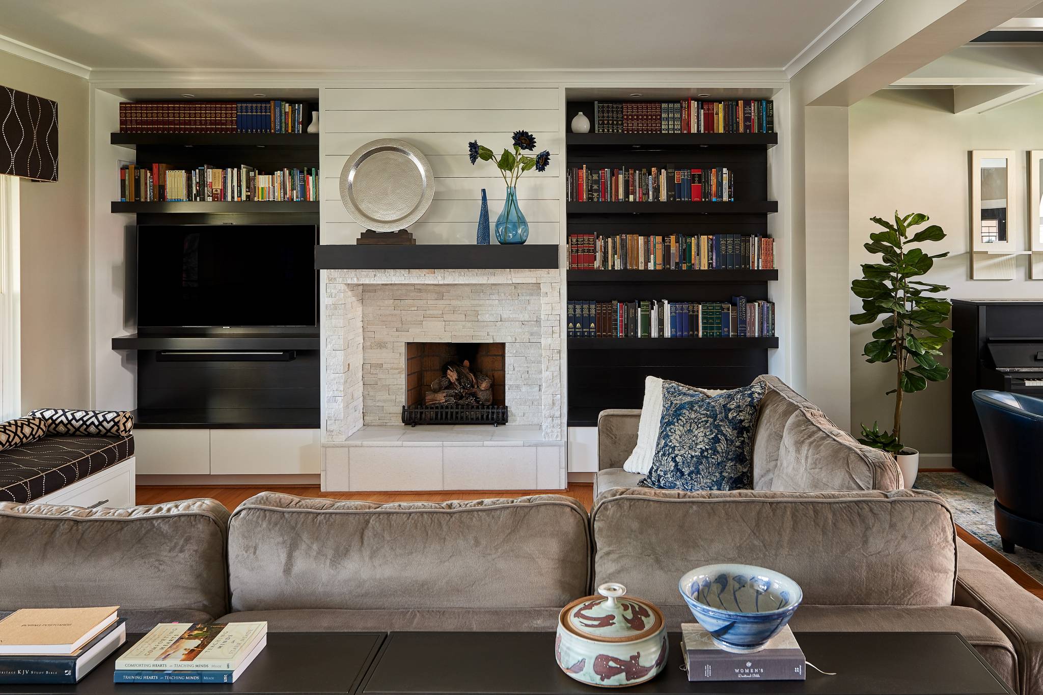 living room renovation with stone fireplace beside tv and built in book shelving sectional couch