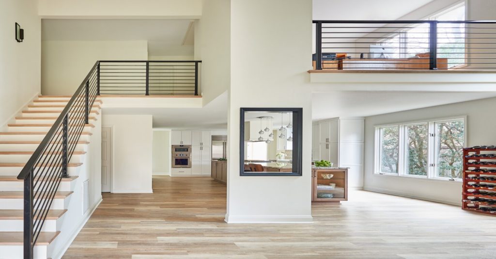 Whole home-remodel with light wood floors, white walls, stairway and loft with black railings.