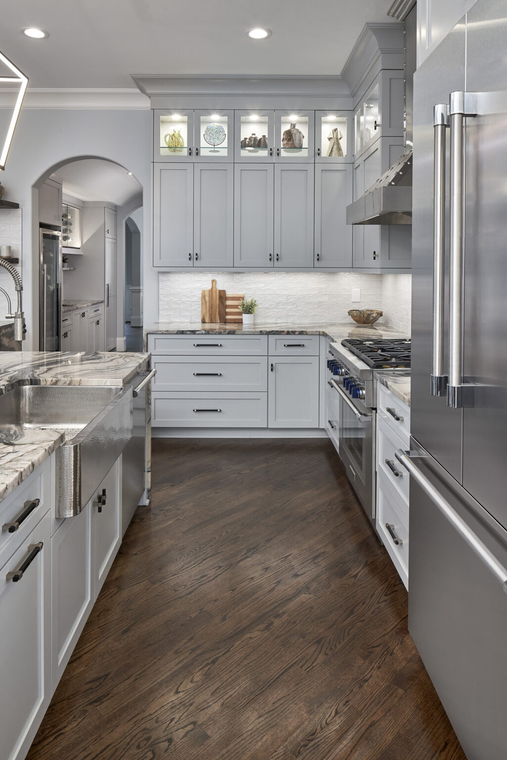 Updated kitchen with diagonal wood floors, white cabinets, stone countertops, and white tile backsplash.