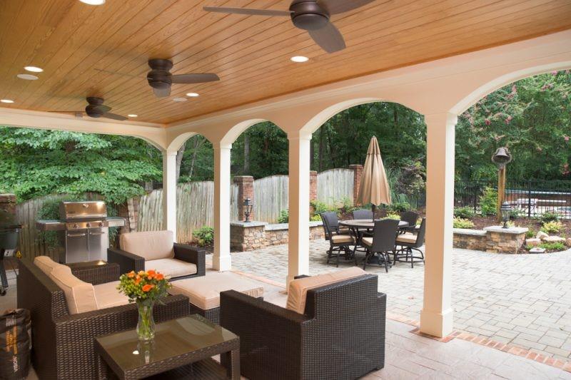 outdoor covered patio with patio furniture and a grill. Wood beam ceiling with three ceiling fans.