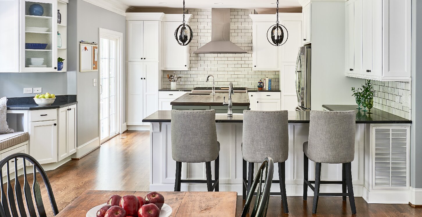 Kitchen remodel with peninsula counters, stool seating, and white backsplash. White cabinets. Wood floors.