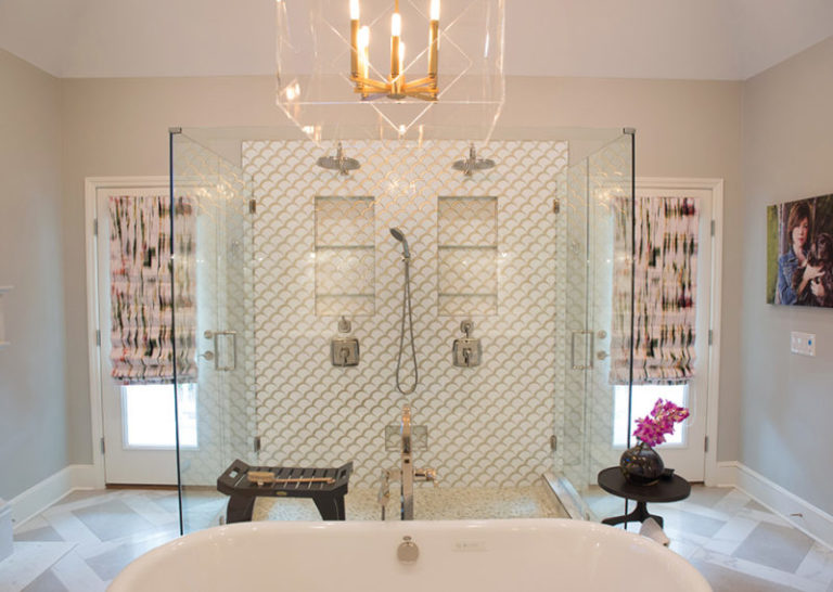 Large full-glass shower with double showerheads and niches, freestanding tub, and glass-paned exterior door on either side