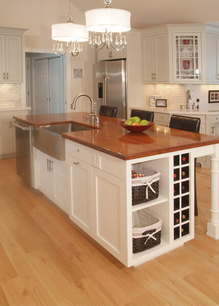 Remodeled kitchen with wood floors, white cabinets, large island with butcher block counter and stainless steel farmhouse sink.