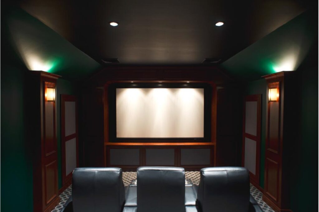 Custom home theatre design with dark green walls and black reclining sofas