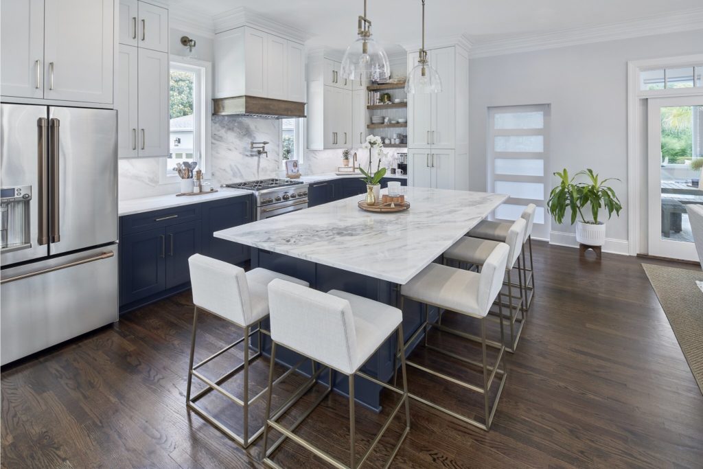 Remodeled kitchen with island and white counter tops, dark wood floors, blue cabinets on bottom and white cabinets on top.