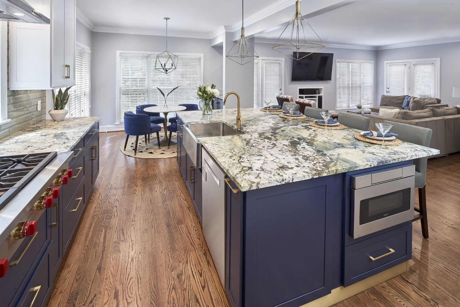 Kitchen island in one-wall kitchen open to living area, with wood floors, dark blue cabinets, gray granite countertops.