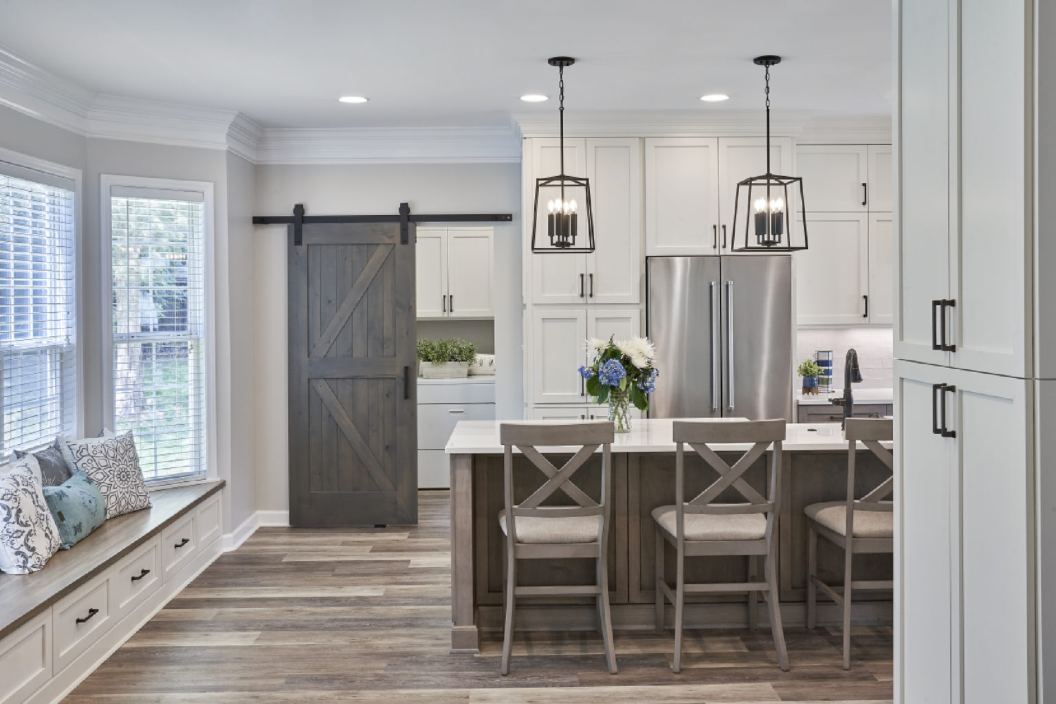 Grey-toned kitchen renovation with window bench and sliding barn door into laundry room
