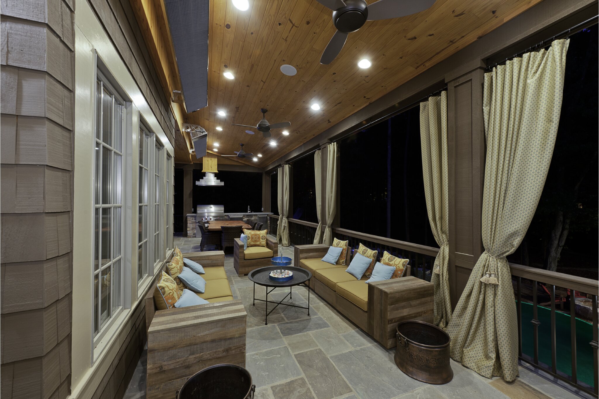 porch renovation in sharon hills with large seats large dining table and hooded vent over stove