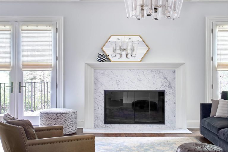Fireplace between two sets of French doors. White walls, white stone surround, white mantel, wood floors.