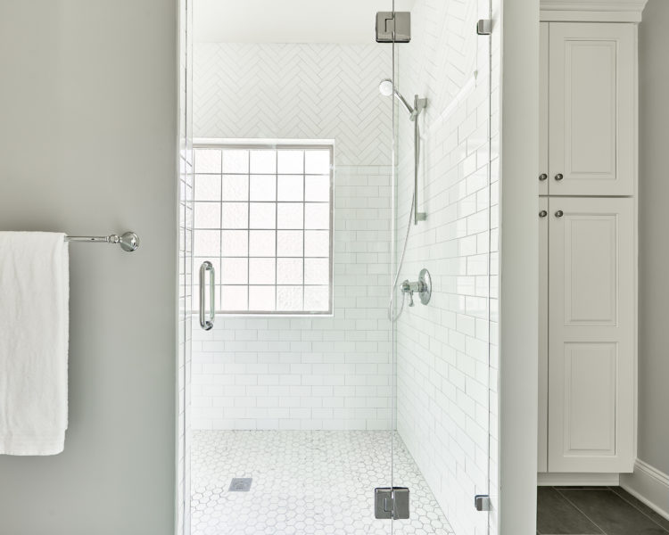 Remodeled white-tile walk-in shower in modern bathroom.