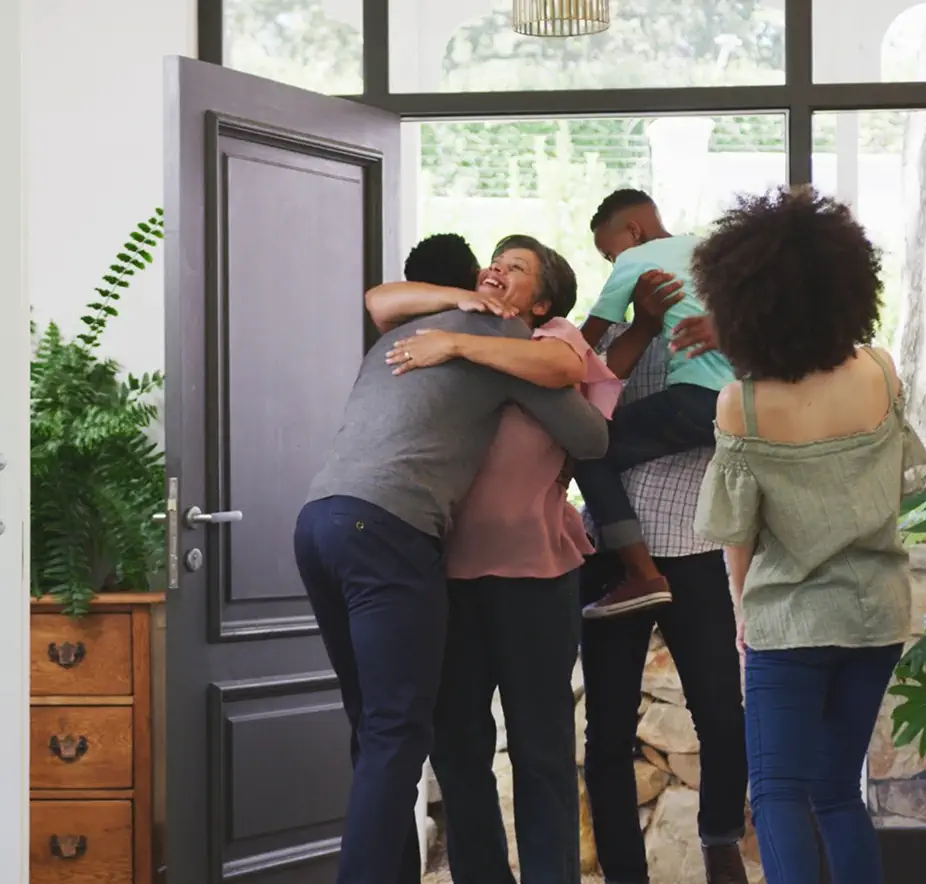Family greeting each other with hugs in a modern home entryway.