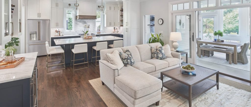 Open kitchen and living room renovation, bright indoor-outdoor living, open sunroom sliding door, wood floors, marble countertops in kitchen.