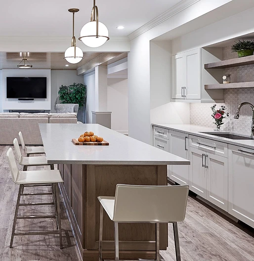 Modern white kitchen with a large island, bar seating, open shelving, and adjacent living area.