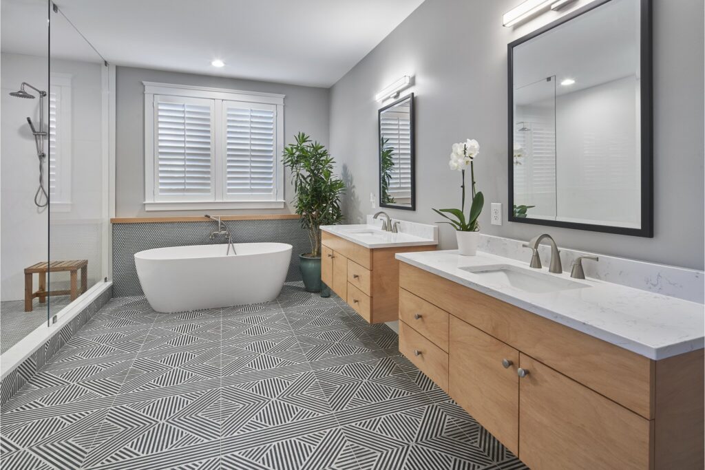 Bathroom remodel with black and white tile, bathtub and light wooden vanity