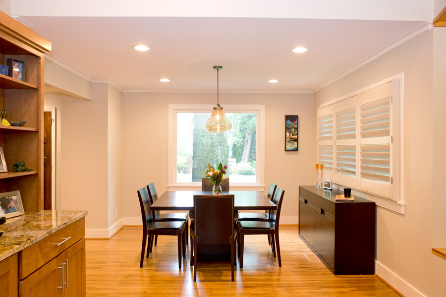 Newly added home addition with wood floors, recessed lighting, white walls, large picture window, and dining set in the middle.